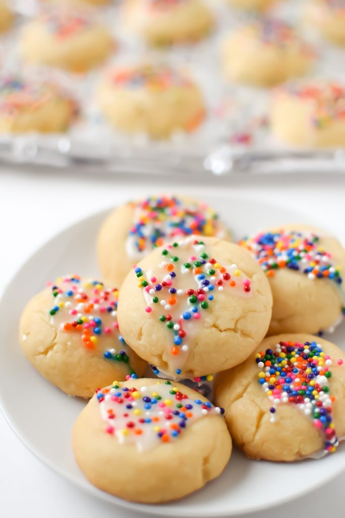 Round light brown traditional Italian spritz cookies with rainbow sprinkles.