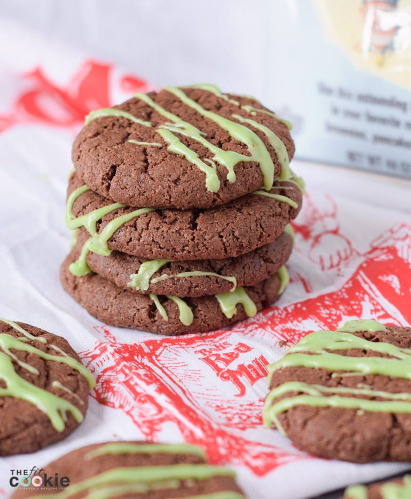 Stack of dark brown peppermint and chocolate vegan Christmas cookies with drizzle of green icing.
