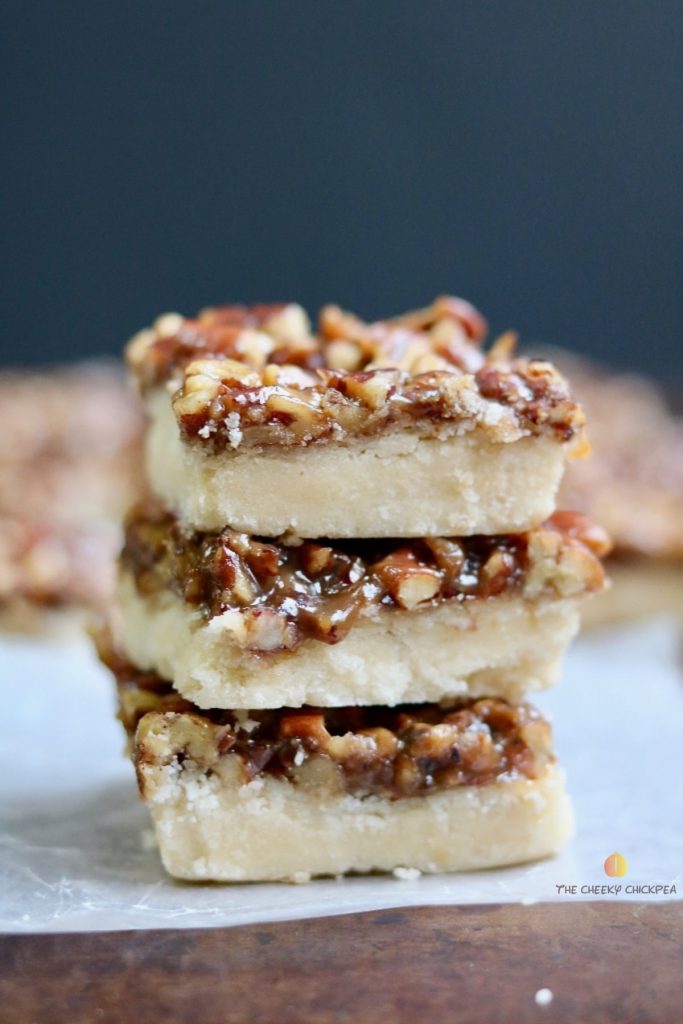 Stack of square vegan salted caramel shortbread with nuts on top.