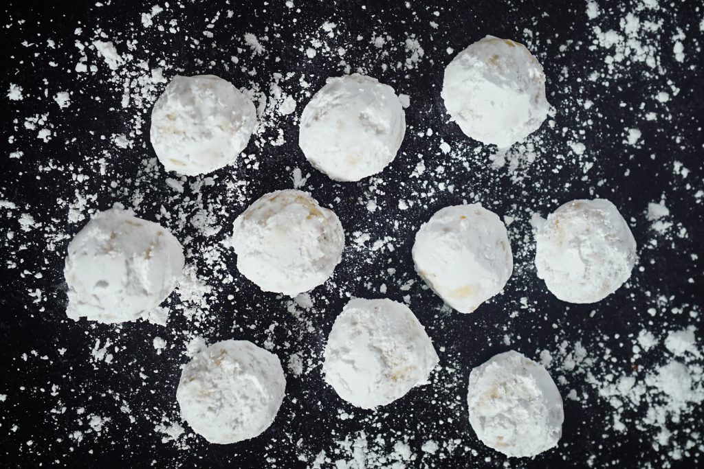 butterball cookies on a tray dusted with sugar