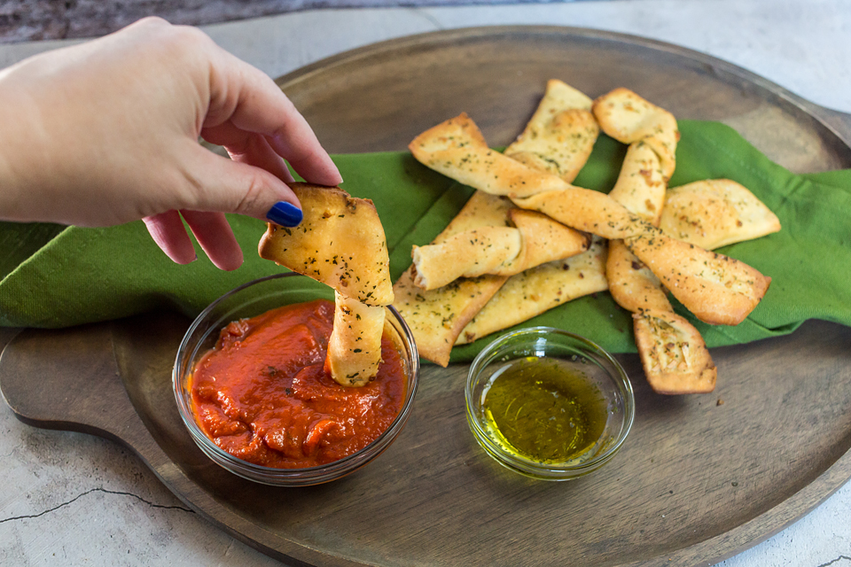 vegan breadsticks being dipped into marinara sauce