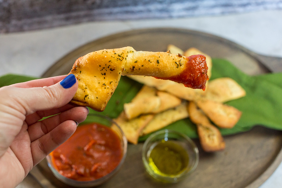 vegan breadsticks being dipped in sauce