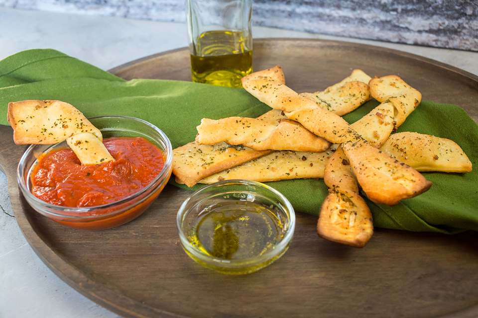 close up on a vegan garlic breadstick being dipped into sauce
