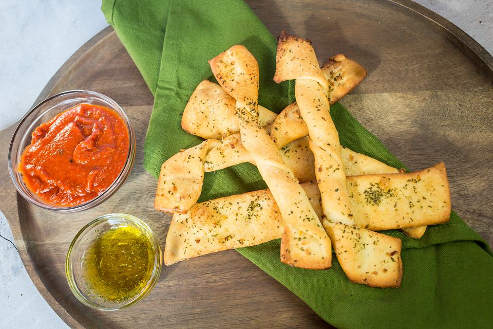 vegan breadsticks on plate with olive oil and sauce