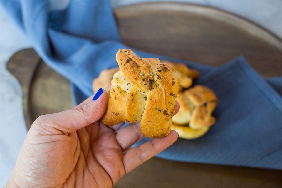 hand holding a vegan garlic knot with italian spice blend on it