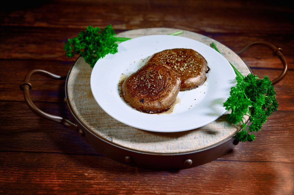 Portobello mushroom steaks on a brown wood background