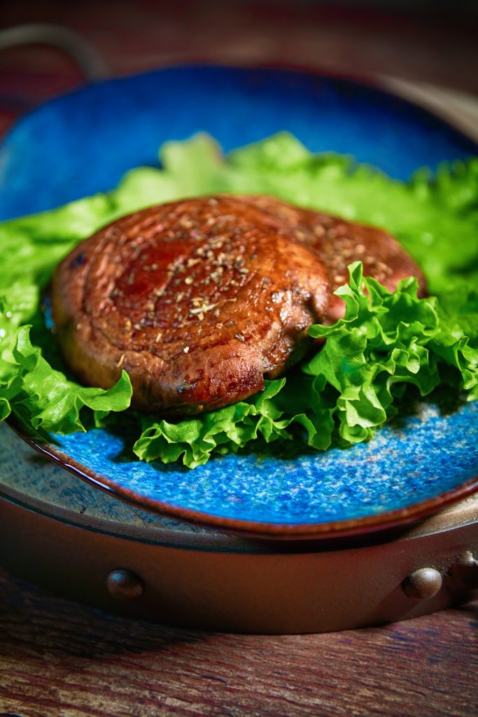 close up on Portobello steaks on a bed of lettuce and blue plate