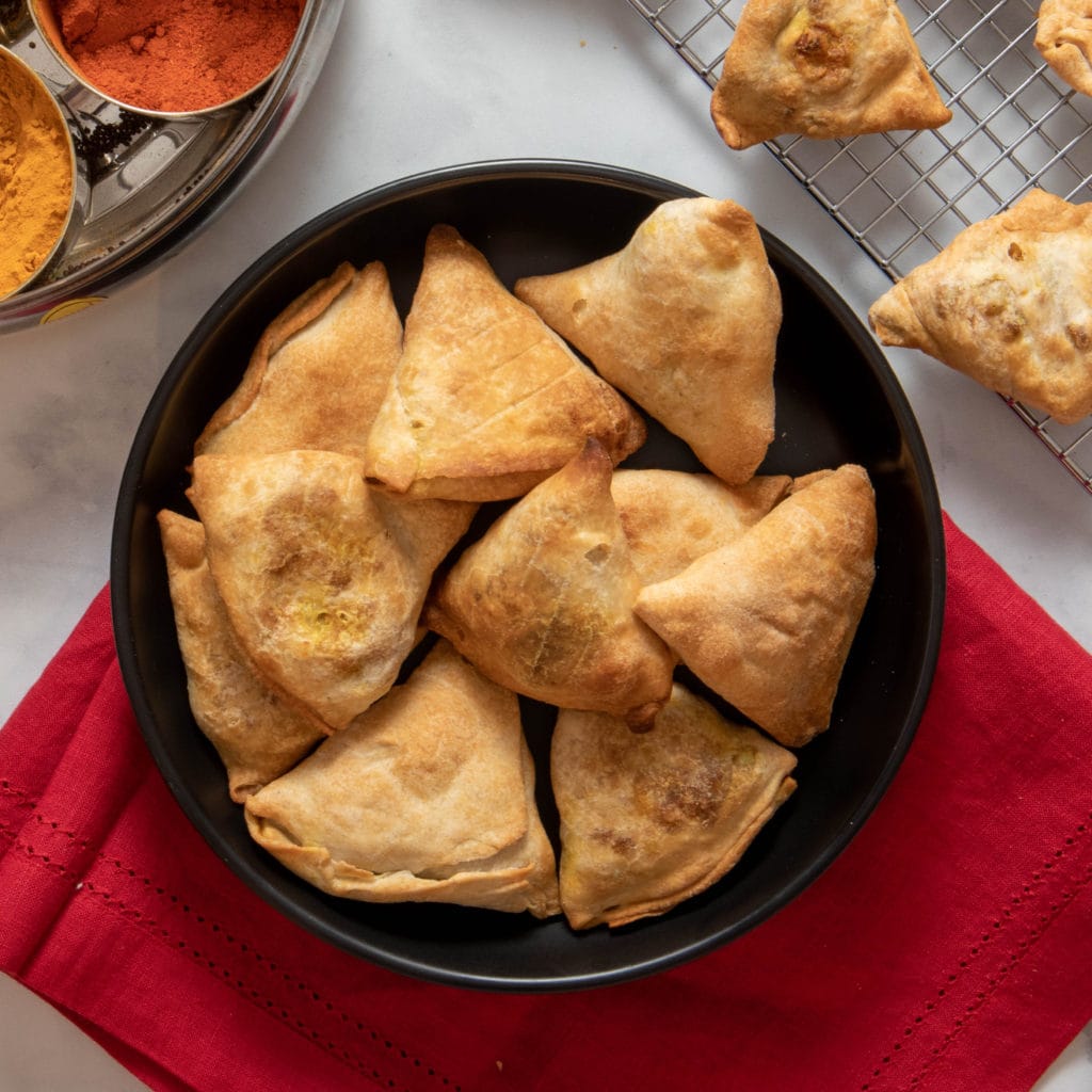 Photo of a black round bowl serving healthy samosas. 