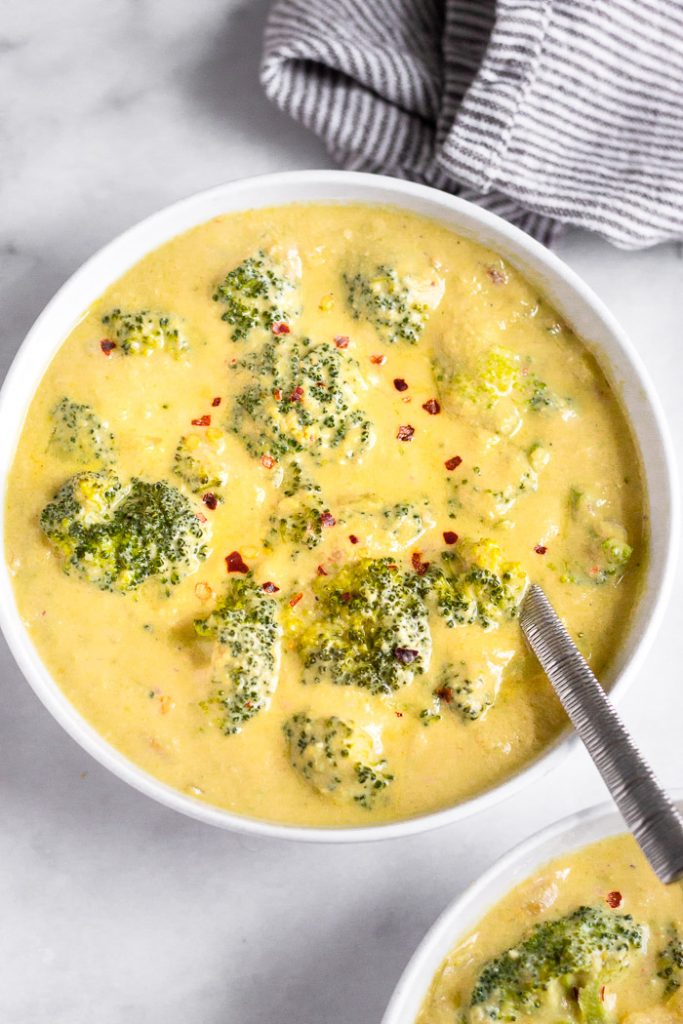 Photo of white bowls serving vegan broccoli cheese soup.
