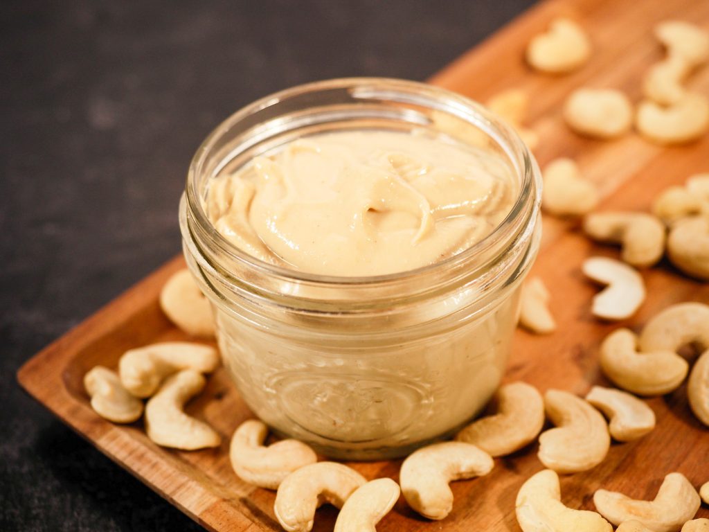 homemade cashew butter in jar with cashews on table
