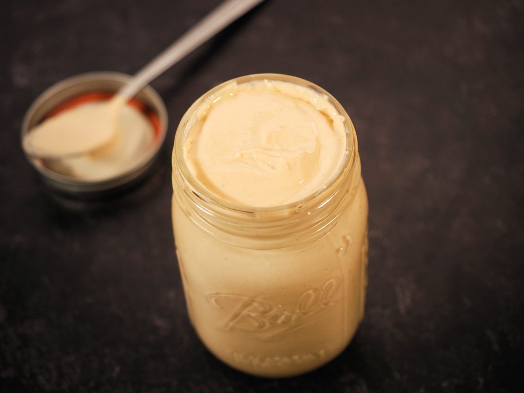 spoon laying on the side of homemade cashew butter that is vegan and creamy