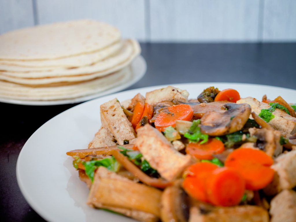 close up of moo shu vegetables with chinese pancakes in the background