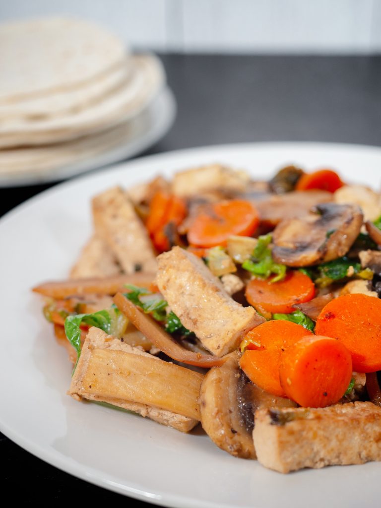 vertical shot of moo shu vegetables with chinese pancakes on black countertop