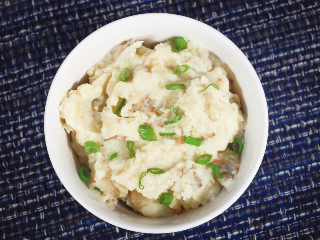 vegan mashed potatoes recipe on blue place mat with green onions