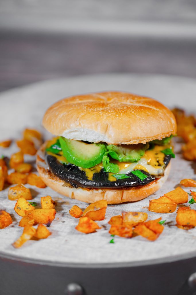 vertical image of a portabello mushroom burger with potatoes