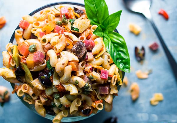 Photo a a small round plate overflowing with Italian vegan pasta salad. Of the vegan Italian recipes, this one will be a picnic favorite.