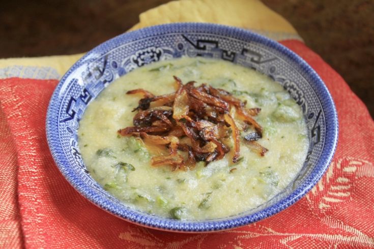 Photo of a blue and white bowl serving polenta on a red cloth napkin. 