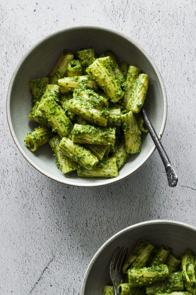 Photo of two bowls serving rigatoni with parsley walnut pesto. 