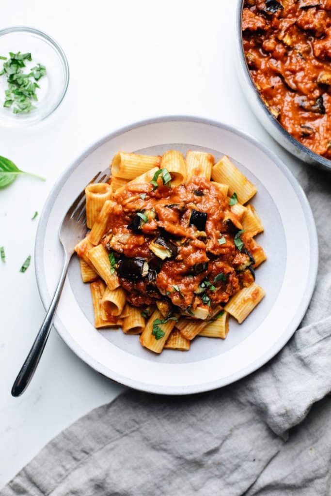 Photo of a round white plate serving roasted eggplant pasta. 