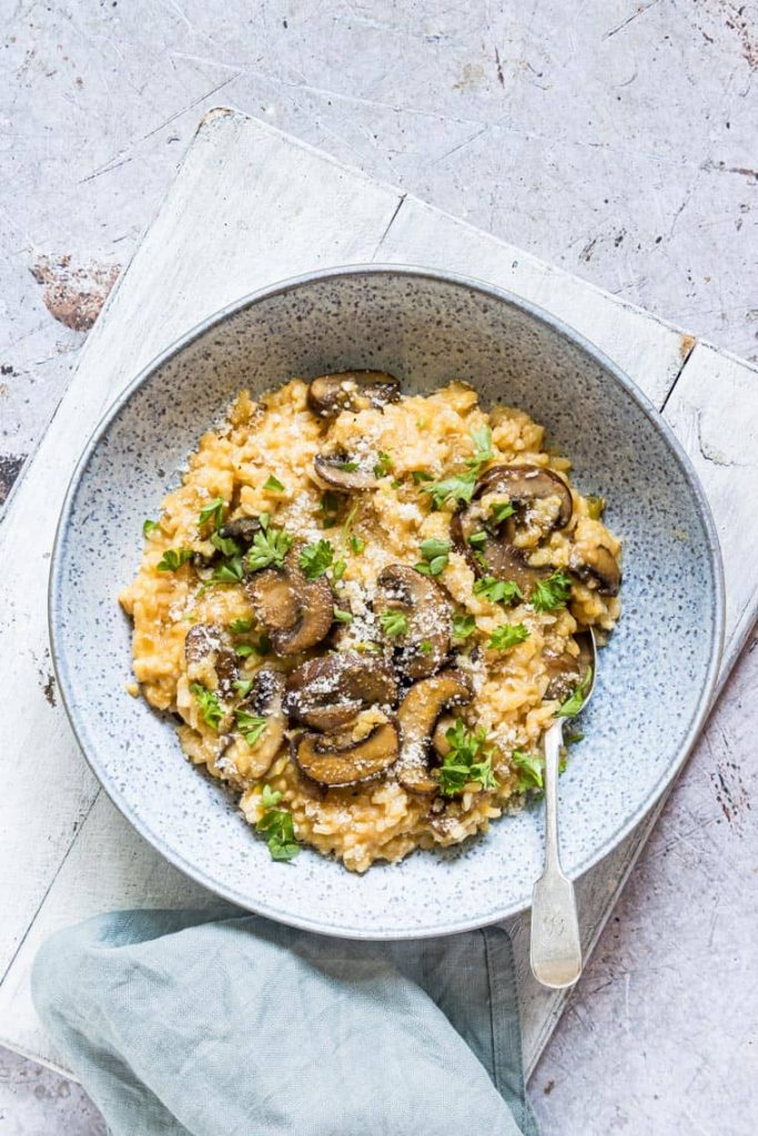 Photo of mushroom risotto with pumpkin being served in a round plate. 