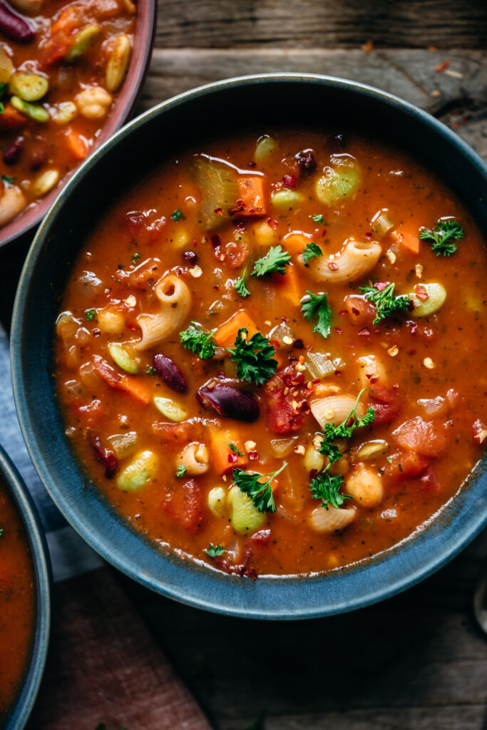 Photo of a blue bowl serving vegan minestrone soup, a classic favorite among vegan Italian recipes.