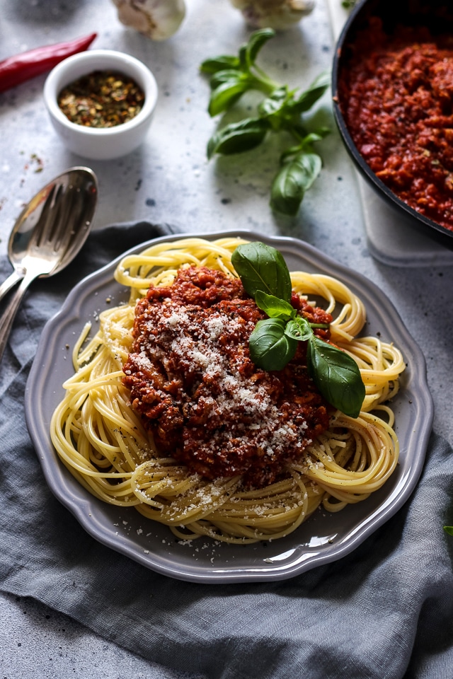 Photo of a light blue plate serving a generous portion of spaghetti with vegan bolognese. 