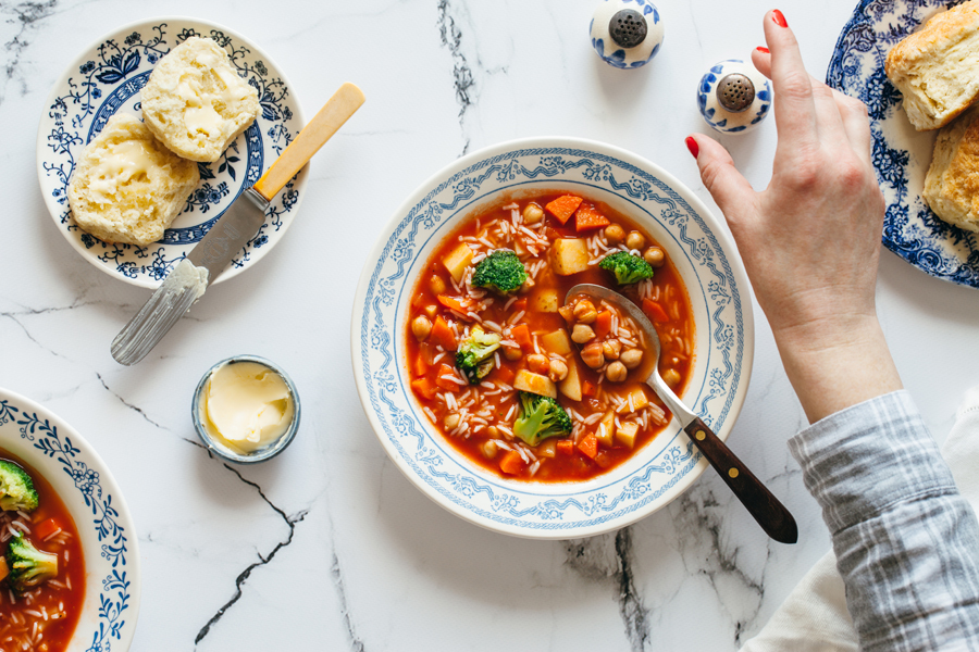 Photo of minestrone soup with chickpeas and rice being served in a white bowl with blue design around the rim.