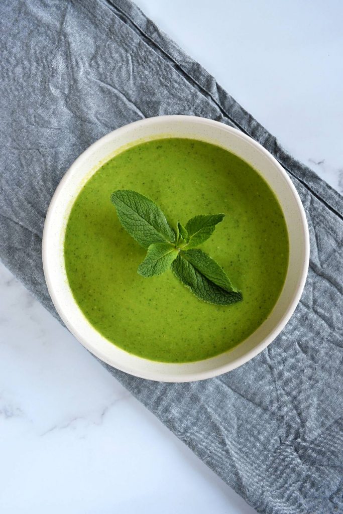 Photo of minty pea soup being served in a round white bowl. 