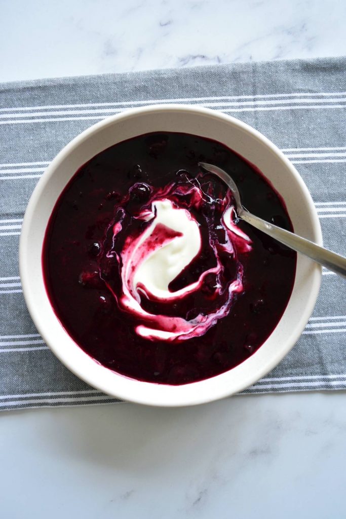 Photo of chilled swedish blueberry soup being served in a round white bowl. Definitely a stand out among the vegan soup recipes.
