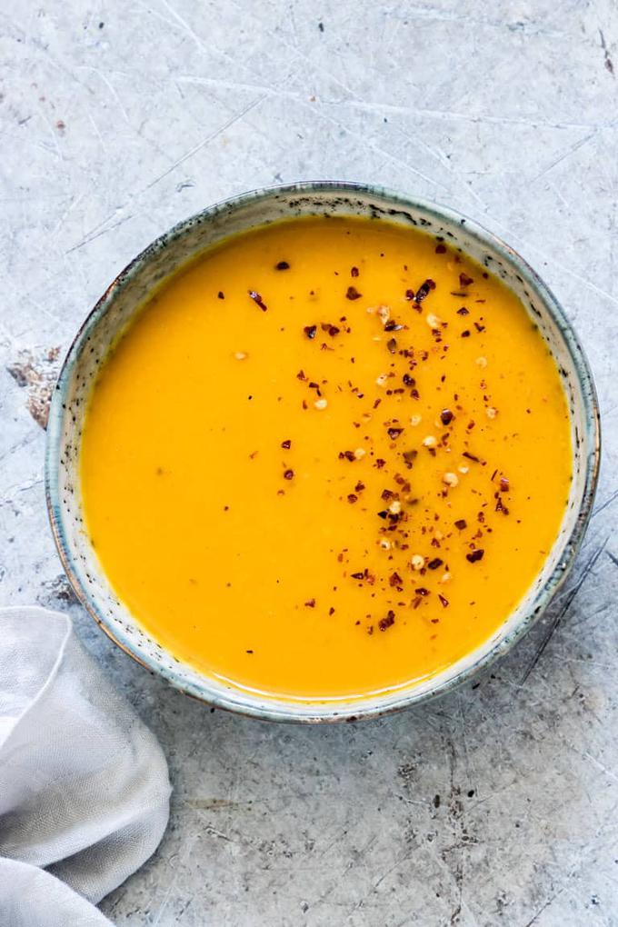 Photo of peanut butter kabocha squash soup being served in a round rustic bowl.