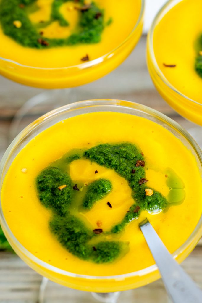 Photo of creamy vegan carrot soup with parsley pistou being served in martini glasses.