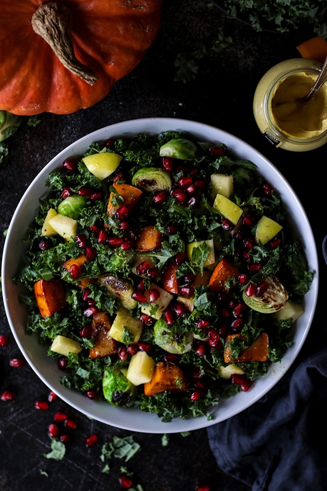 Photo of vegan fall harvest salad with kale and pumpkin being served in a large round white bowl.