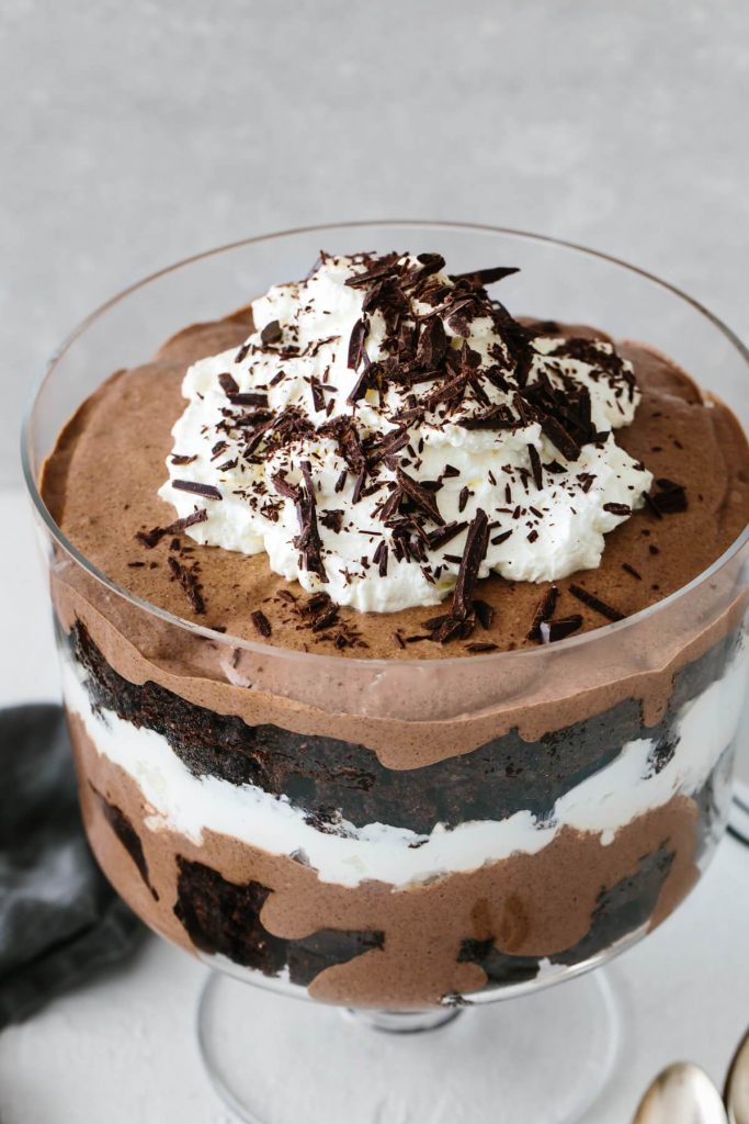 Photo of a brownie trifle being served in a large glass bowl. 