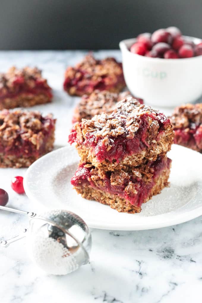Photo of several cranberry oatmeal crumb bars being served with a light dusting on powdered sugar on top.