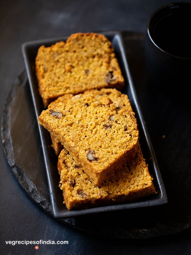 Photo of a few slices of vegan pumpkin bread being served on a dark rectangular plate.