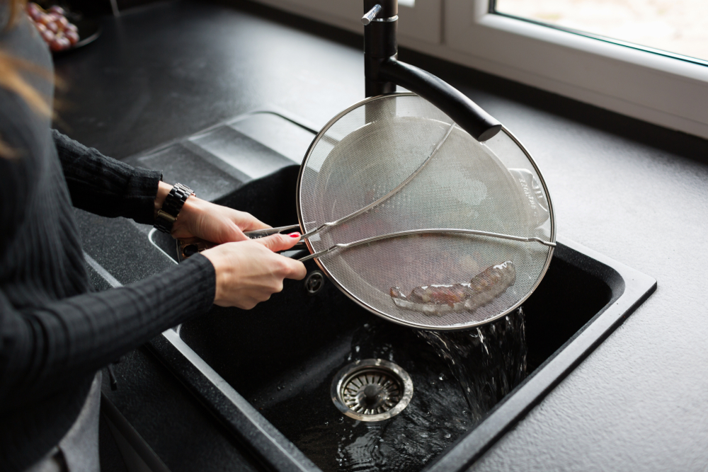 Woman washing a grease splatter guard