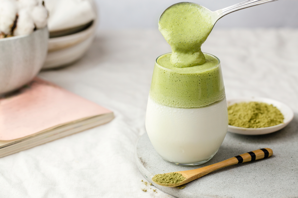 dalgona matcha whipped latte being poured into a cup