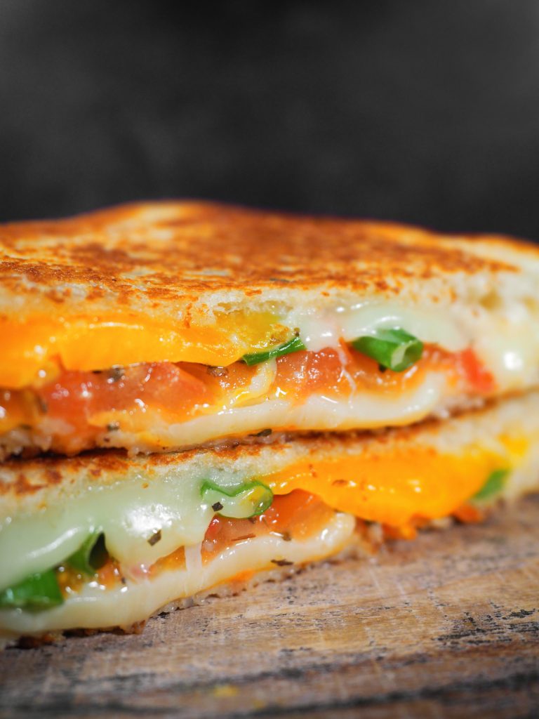 close up photo of grilled cheese with tomato and veggies