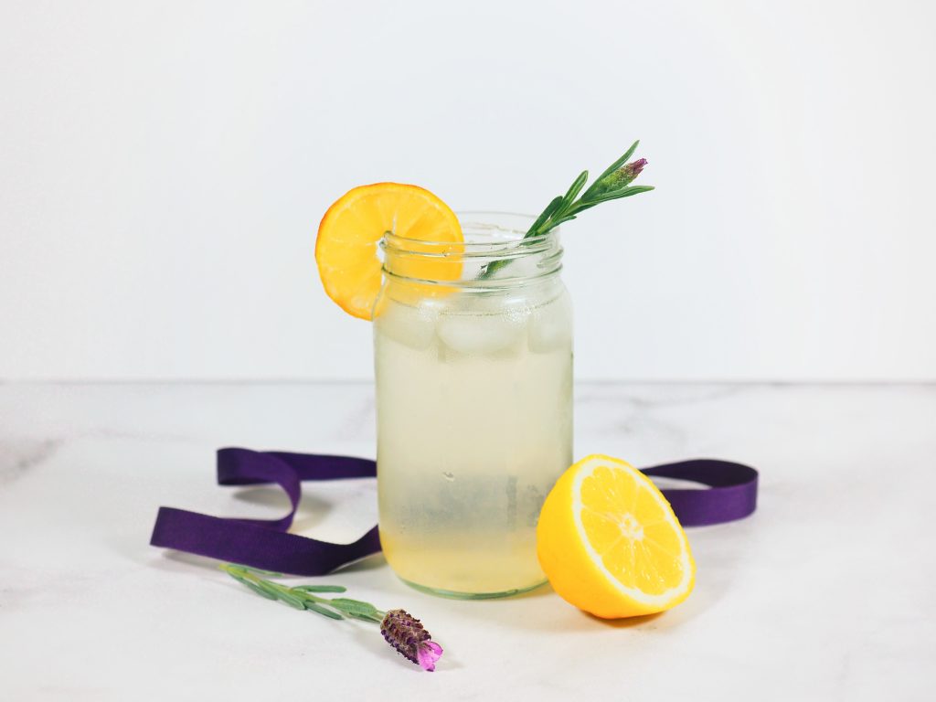 lavender lemonade in glass jar with lemons and lavender on countertop