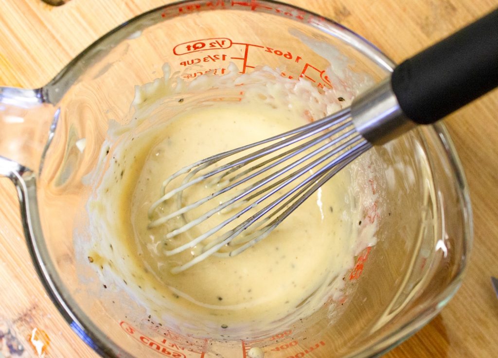 whisk in measuring cup of tahini maple dressing