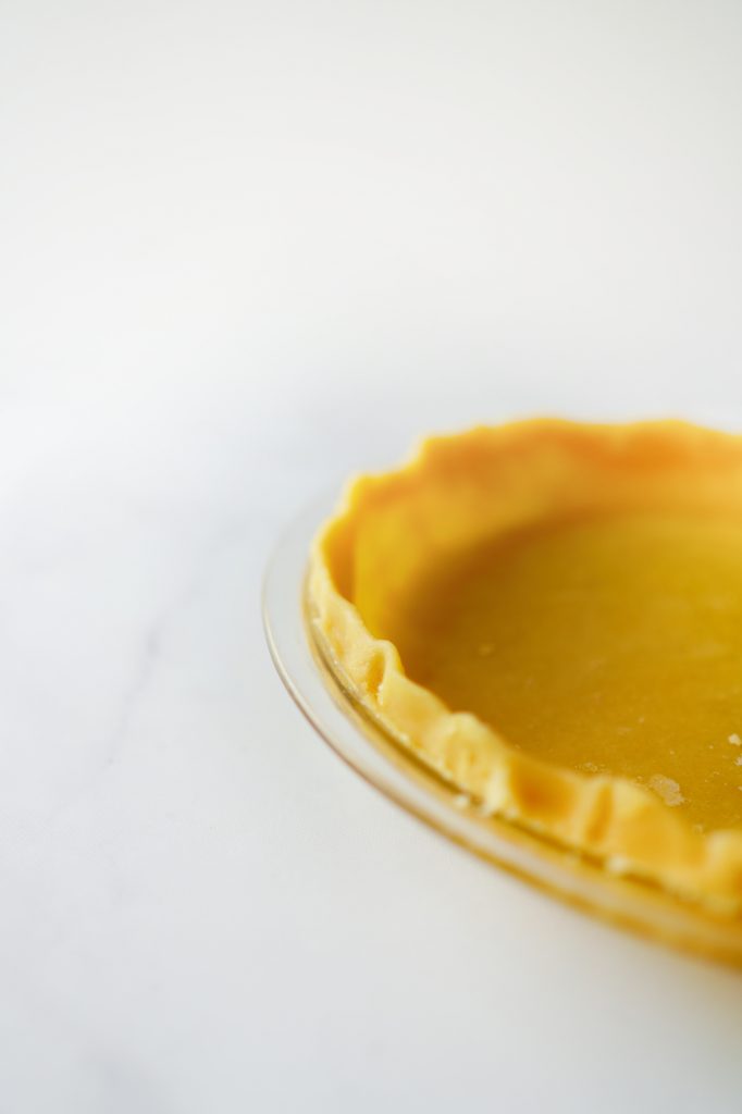 Close up of side of flaky pie crust on a marble counter.