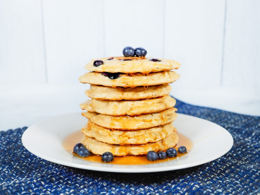 vegan blueberry pancakes on plate with syrup and fruit