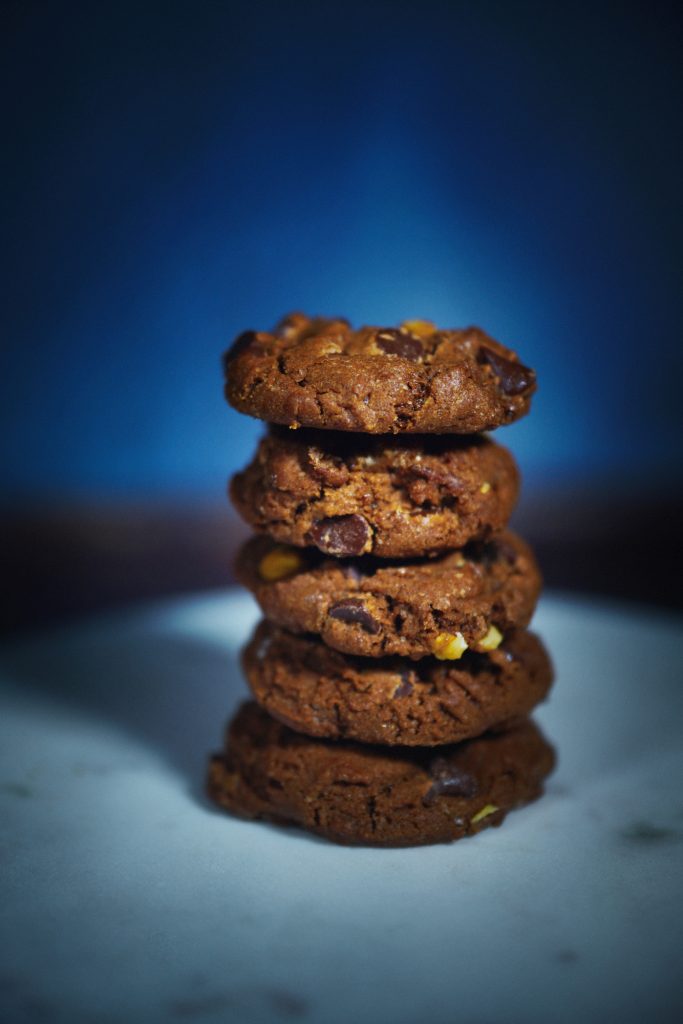 Stacked vegan chocolate cookies with a blue background.