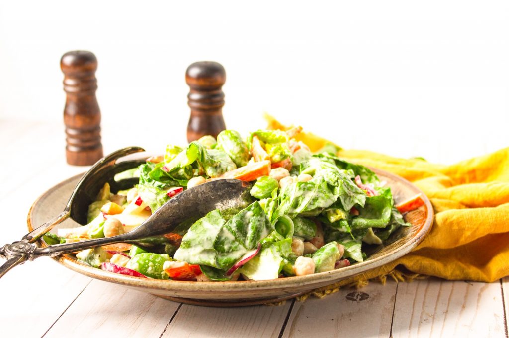 vegan chopped salad on plate with tongs and yellow towel