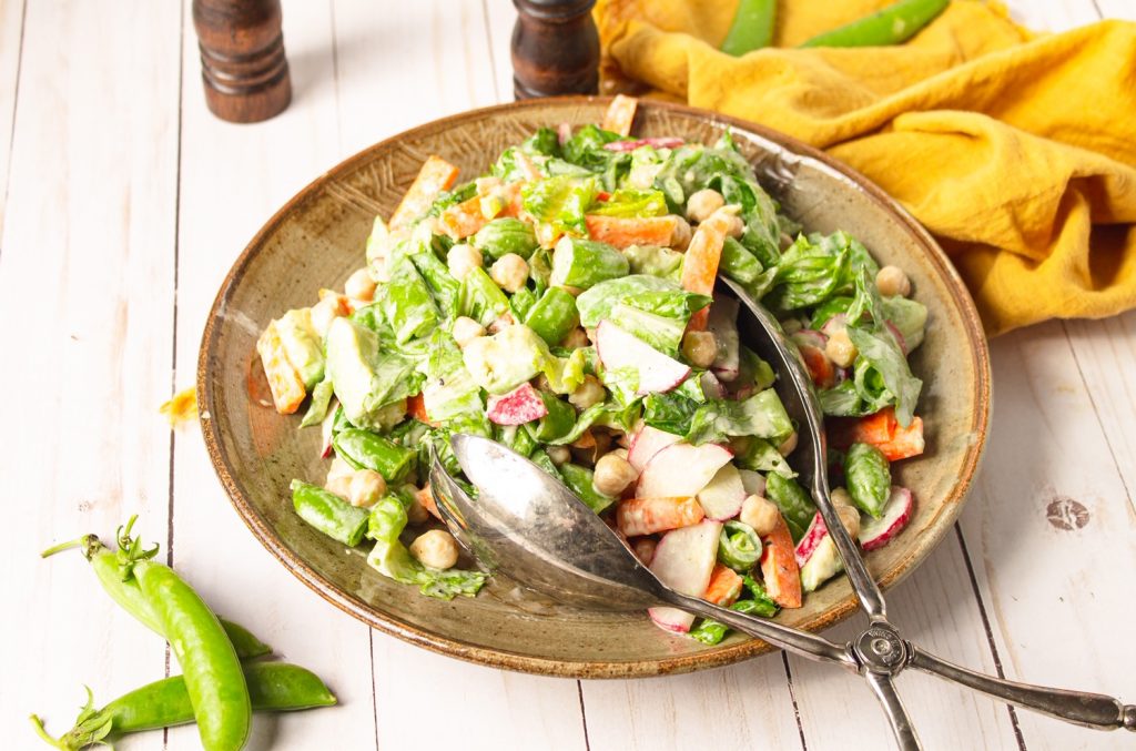 vegan chopped salad on plate with tongs