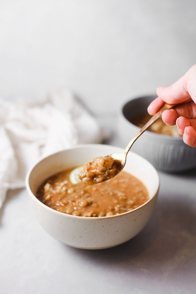 spoon holding vegan recipe of lentil soup