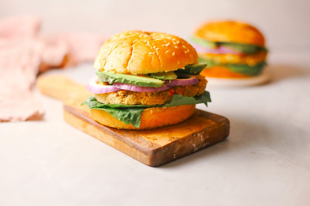 Photo of a 15 minute chickpea burger being served on a wooden board. A vegan Mother's Day recipe for moms that prefer savory over sweet. 