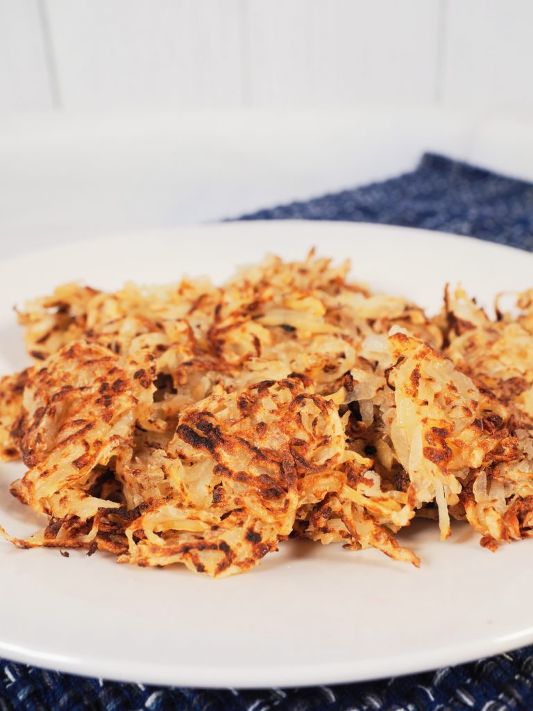 Photo of vegan hash browns being served on a round white plate.