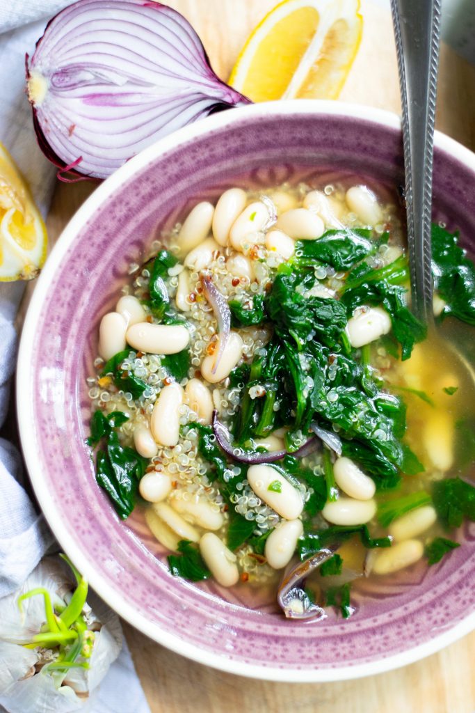 Photo of vegan white bean soup being served in a small round bowl. Makes a perfect pairing with salad for your vegan Mother's Day brunch. 