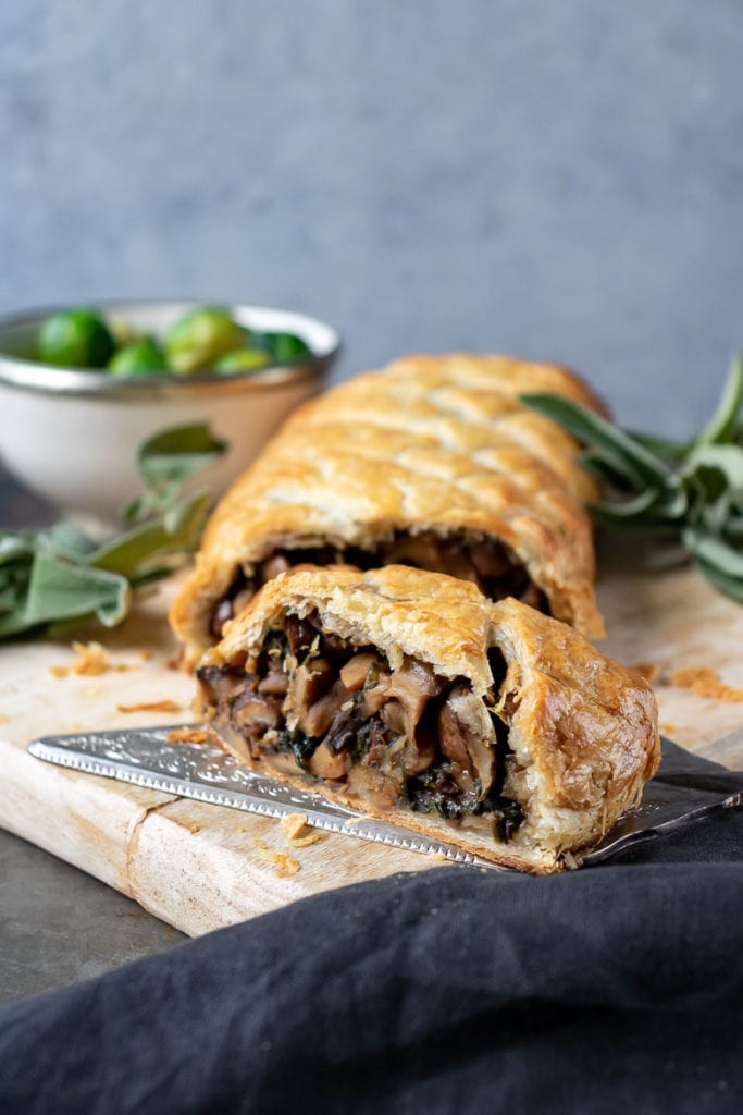 Photo of mushroom wellington being served on a wooden board. 